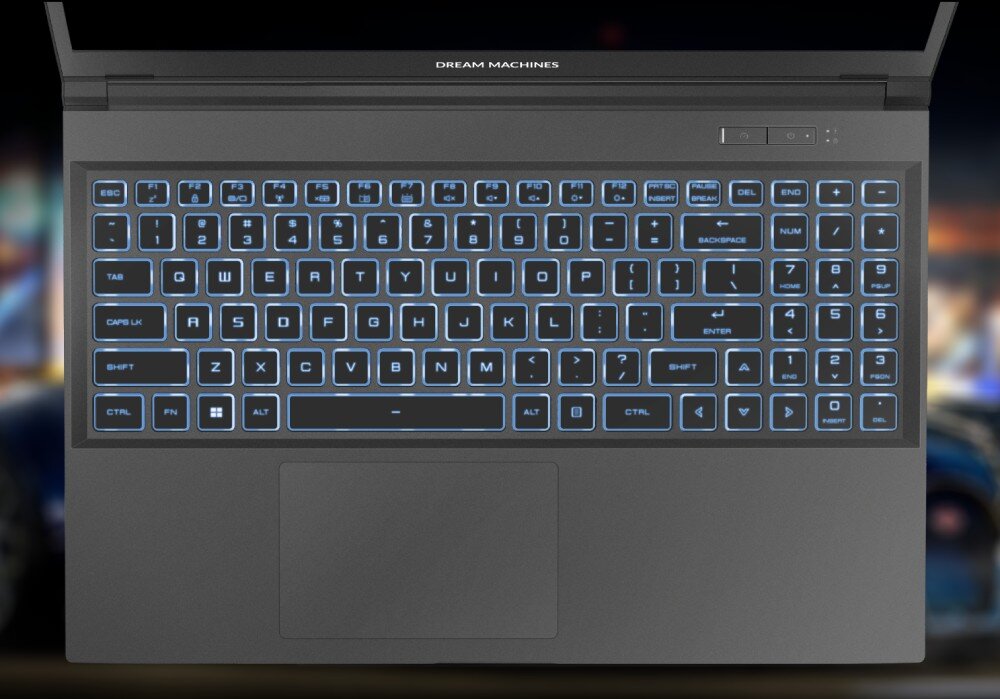 Widok z góry na podświetlaną na niebiesko klawiaturę laptopa gamingowego Dream Machines, z pełnowymiarowym układem i blokiem numerycznym, na tle rozmytej sceny z gry wyścigowej. - klawiatura podświetlenie