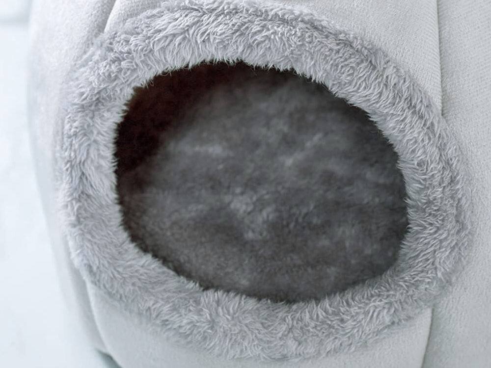 Legowisko dla kota ZWIERZOPASJA Amber bezpieczne wejście dla zwierząt szary wygoda mały piesek komfortowe wymiary 37x37x33 cm Ekstremalne zbliżenie na wejście do domku. Wyraźnie widoczne jest obszycie z miękkiego, futrzanego materiału w kolorze szarym oraz futrzane wypełnienie wnętrza, zapewniające ciepło.