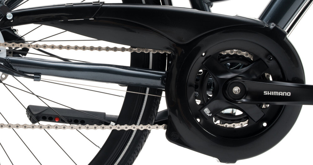 Zdjęcie przedstawia część roweru z widocznym mechanizmem napędowym i łańcuchem. Na osłonie mechanizmu znajduje się napis \'SHIMANO\'.