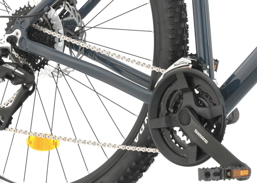 Rower górski MTB INDIANA X-Pulser 2.9 M19 29 cali męski Srebrno-grafitowy zbliżenie na korbę wolnobieg i łańcuch lekka wydajna konstrukcja korby korba SHIMANO typu FC-TY301 kaseta SHIMANO typu CS-HG318134-8S solidność wytrzyma bardzo duży nacisk na pedały