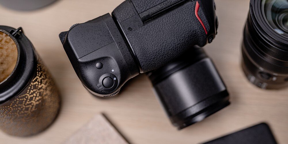 Rzut z góry na lustrzankę Nikon Z8 na drewnianym blacie w otoczeniu aparatu obiektywu fotograficznego i lampionu