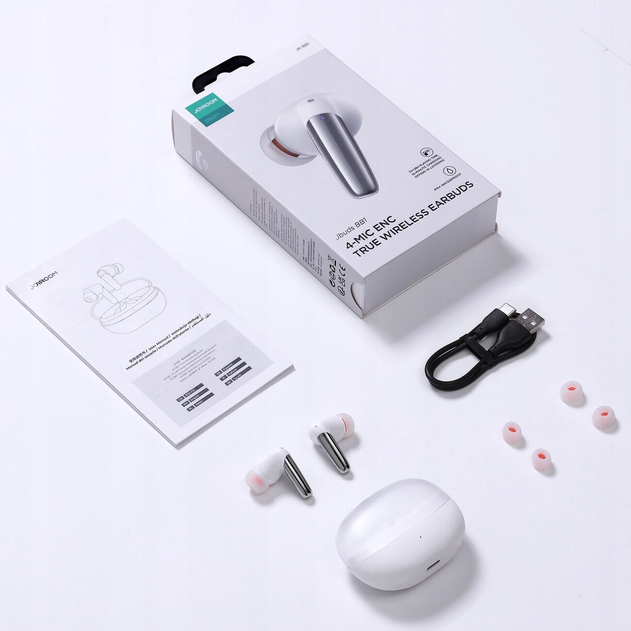Na obrazie widoczne są bezprzewodowe słuchawki douszne z mikrofonem, etui ładujące, kabel USB, dodatkowe gumki oraz instrukcja obsługi. Opakowanie produktu zawiera napis \'4 MIC ENC TRUE WIRELESS EARBUDS\'.