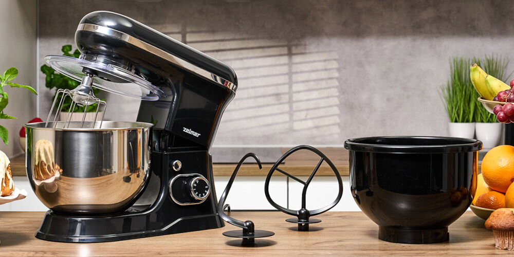 Robot planetarny ZELMER ZKR1355 1200W czarny robot stojący na blacie otwarta pozycja zamontowane mieszadło i osłona srebrna misa pokrętło dwie końcówki stoją na blacie i czarna misa dwie misy 4,5-litrowa plastikowa 5-litrowa ze stali nierdzewnej do przygotowywania deserów praktyczna osłona porządek wygoda podczas pieczenia 