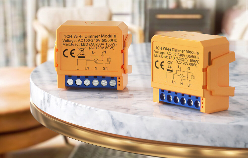Na marmurowym blacie znajdują się dwa pomarańczowe moduły ściemniacza Wi-Fi z oznaczeniami technicznymi i symbolami CE. Widoczny jest tekst: \'1CH Wi-Fi Dimmer Module Voltage: AC100-240V 50/60Hz Max.load: LED (AC230V 150W) (AC120V 80W)\'.