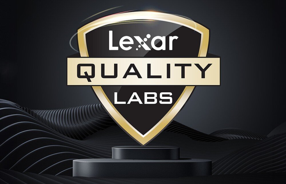 Dysk LEXAR SL600 Graficzny logotyp 'Lexar Quality Labs' wpisany w kształt tarczy, umieszczony na czarnym postumencie na tle ciemnych falistych linii