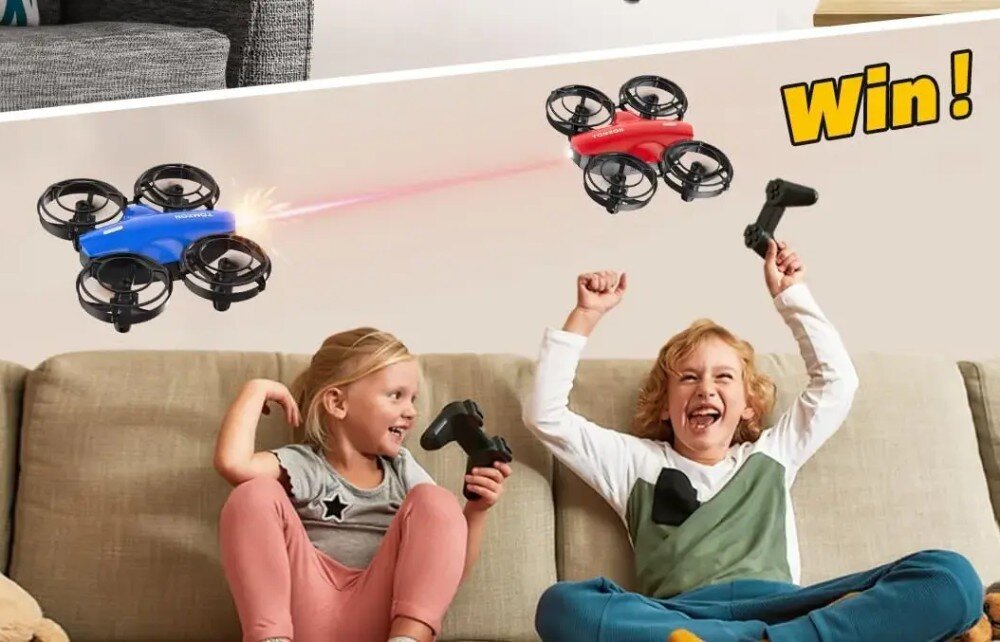 Dron EXTRALINK A24 Dwoje dzieci siedzących na kanapie z kontrolerami w dłoniach cieszy się z zabawy dwoma małymi dronami, z których jeden celuje czerwoną wiązką światła w stronę drugiego