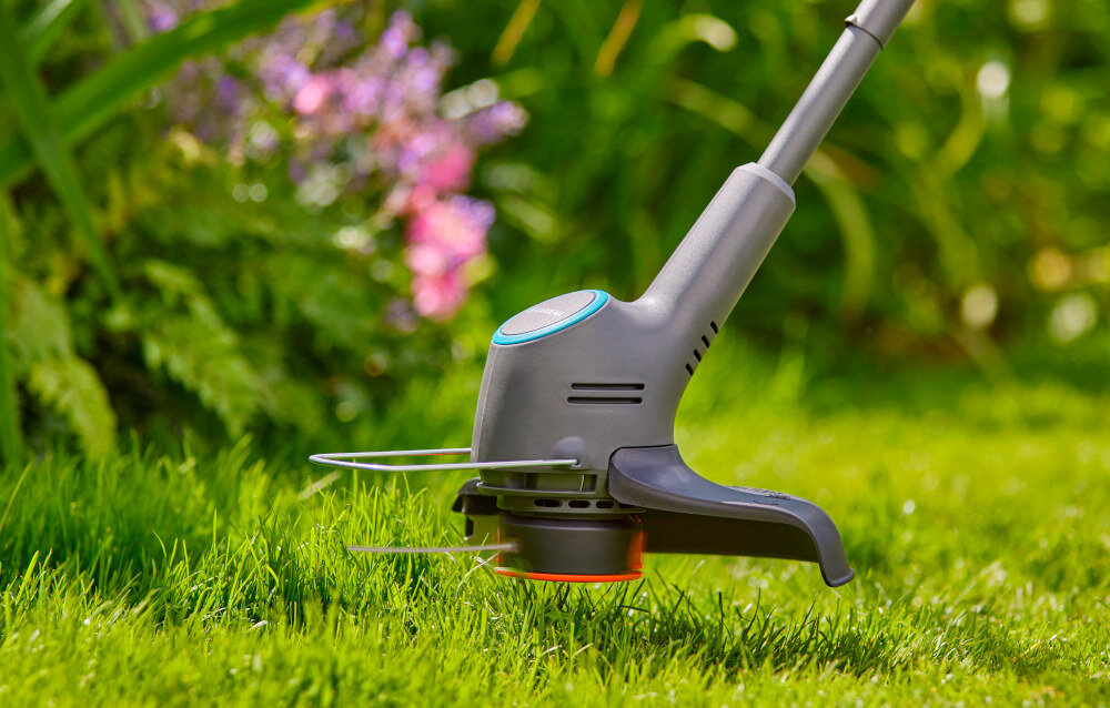 Podkaszarka akumulatorowa GARDENA EasyTrim 14704-20 zbliżenie na głowicę widoczna osłona roślin w tle kwiaty osłona roślin ochrona delikatnych roślin przed uszkodzeniem