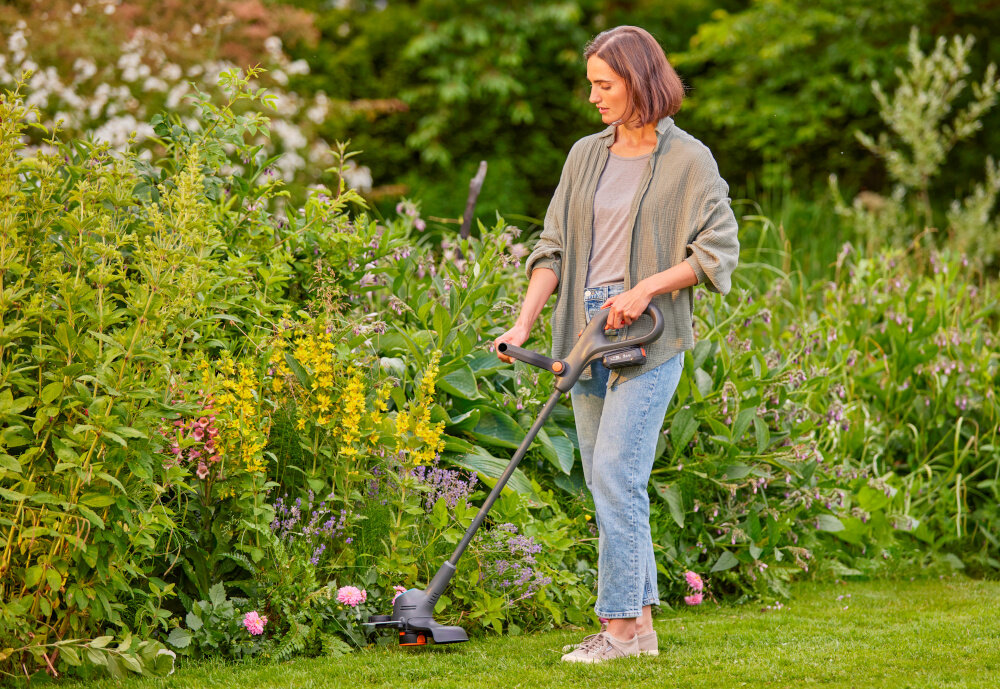 Podkaszarka akumulatorowa GARDENA EasyTrim 14704-20 osoba tnie trawę wzdłuż rabaty kwiatowej w tle rośliny silnik bezszczotkowy większa wydajność i trwałość prędkość obrotowa do 9500 obr./min działa sprawnie, zużywa mniej energii i wymaga rzadszej konserwacji hałas na poziomie 75 dB przy uchu operatora niski poziom wibracji 2,8 m/s² komfort i małe zmęczenie rąk