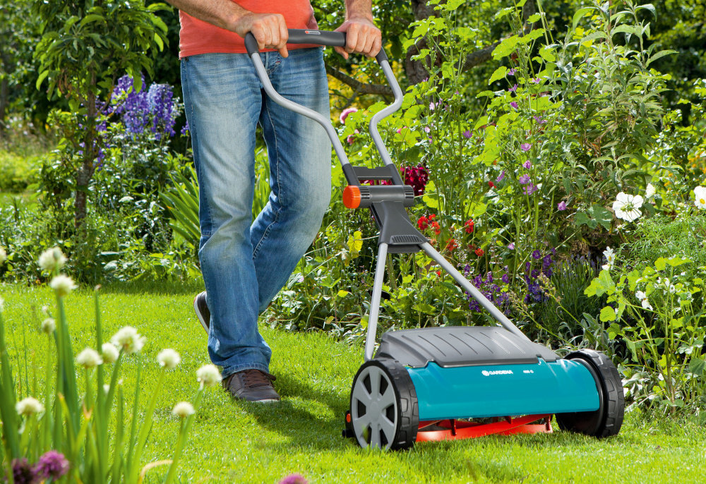 Kosiarka ręczna GARDENA Comfort 400 C regulacja 4-stopniowa 04022-20 ogród trawnik osoba kosi trawę w tle krzewy kwiaty koszenie przycinanie trawy zadbany trawnik