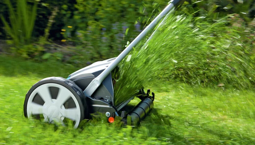 Kosiarka ręczna GARDENA Comfort 400 C regulacja 4-stopniowa 04022-20 trawnik zbliżenie na koła trawa wydobywa się spod kół cylinder tnący wykonany z hartowanej stali pokrycie powłoką antyadhezyjną trwałość odporność na korozję czyste równe cięcia bezdotykowa praca ostrzy minimalizuje ryzyko poszarpania źdźbeł