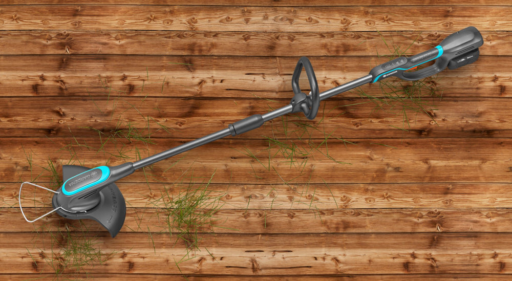 Podkaszarka akumulatorowa GARDENA PowerTrim 30 14703-55 podkaszarka na drewnianej podłodze wydajność komfort pomoc przy pielęgnacji ogrodu zasilanie akumulatorowe