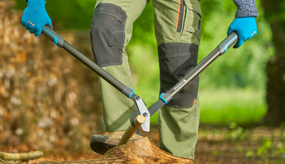 Nożyce do gałęzi GARDENA EnergyCut Pro L 12052-20 ogród drzewa osoba tnie ścięte gałęzie na kawałki stos drzewa cięcie boczne dwa ostrza przesuwają się obok siebie gładka powierzchnia cięcia sprzyja naturalnemu gojeniu się roślin