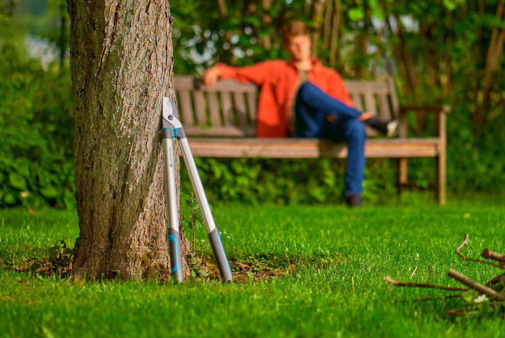 Nożyce do gałęzi GARDENA Easycut L 12031-20 ogród drzewa nożyce oparte o pień drzewa w tle na ławce ogrodowej siedzi osoba wygodne przycinanie gałęzi precyzyjne cięcie