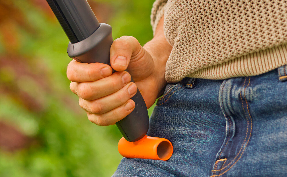 Sekator teleskopowy GARDENA StarCut PRO L 12081-20 zbliżenie na uchwyt osoba opiera sekator o nogę rozmazane tło dolna rękojeść oferuje pewny uchwyt dodatkowy uchwyt w kształcie litery T prosty mechanizm zacisku łatwe w użytkowaniu