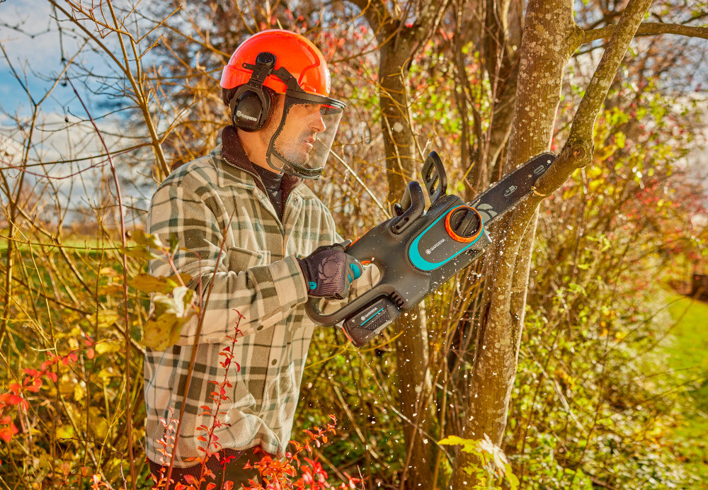 Piła akumulatorowa GARDENA PowerSaw 14790-55 osoba tnie gałęzie w tle ogród łańcuch półdłutowy o niskoprofilowej podziałce 3/8” grubości ogniwa 1,1 mm gładkie i precyzyjne cięcie wyższa tolerancja na zanieczyszczenia równomierne cięcie