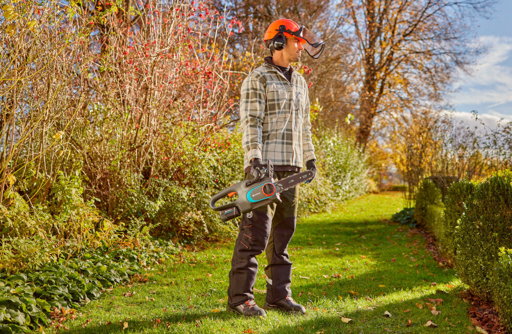 Piła akumulatorowa GARDENA PowerSaw 14790-55 ogród drzewa krzewy osoba trzyma piłę w dłoniach solidna prowadnica łańcuch Oregon® brak konieczności stosowania narzędzi do napinania łańcucha system smarowania LubriTec nie wymaga skomplikowanej konserwacji