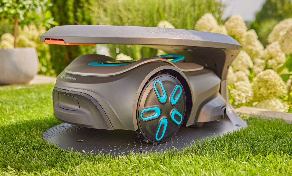 Garaż dla robota koszącego GARDENA Sileno Max Free 15025-20 ogród trawnik robot koszący umieszczony w garażu w tle kwiaty solidne akcesorium ochrona dla robota koszącego bezpieczne przechowywanie