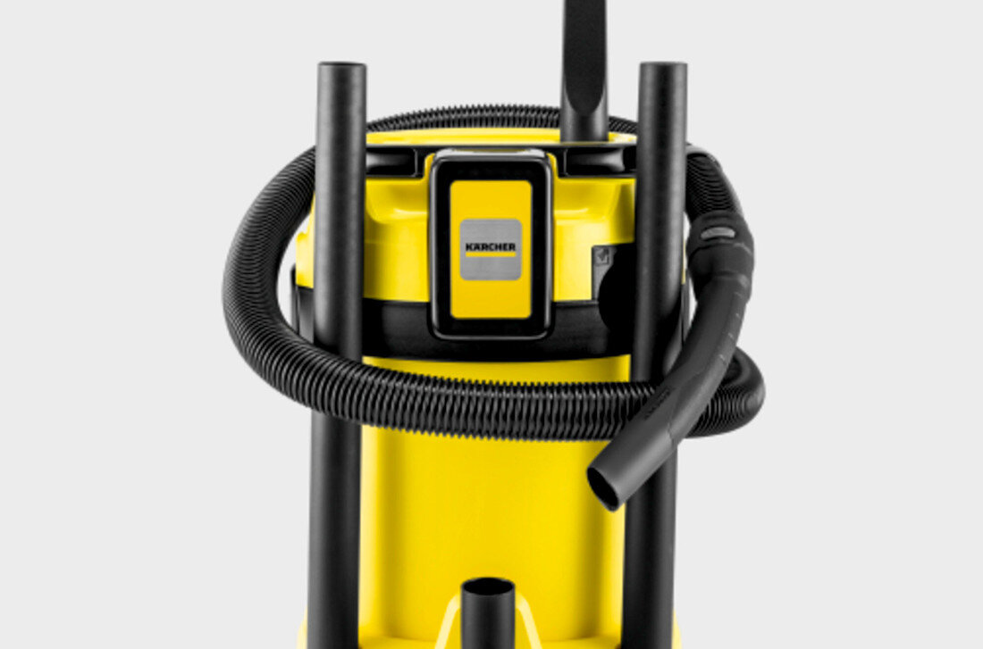 Na obrazie widoczny jest żółty odkurzacz z czarnymi elementami, w tym wężem i uchwytami. Na przedniej części znajduje się logo \'KARCHER\'.