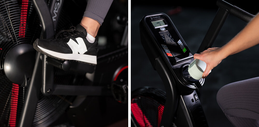 Rower powietrzny HMS MP5420 pokazanie detale pedał roweru komputer rower w całości oraz kobieta trenująca uchwyt na bidon i telefon kółka transportowe zasilanie komputera 4 dołączonymi bateriami AA