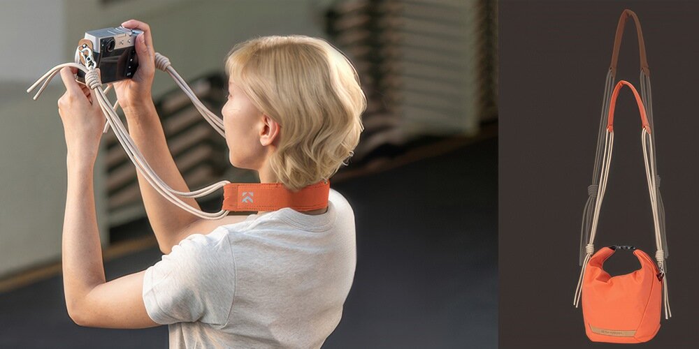 Kobieta fotografuje aparatem na pasku, obok pomarańczowa torba fotograficzna z regulowanym paskiem pokazana na ciemnym tle