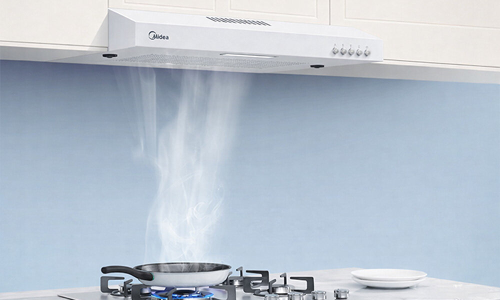 OKAP MIDEA MH60F17EM21WB Ilustracja ukazuje okap pochłaniający parę unoszącą się z patelni podgrzewanej na kuchence gazowej. Widoczny strumień pary podkreśla działanie urządzenia przyciski regulacja skokowa 3 poziomy mocy