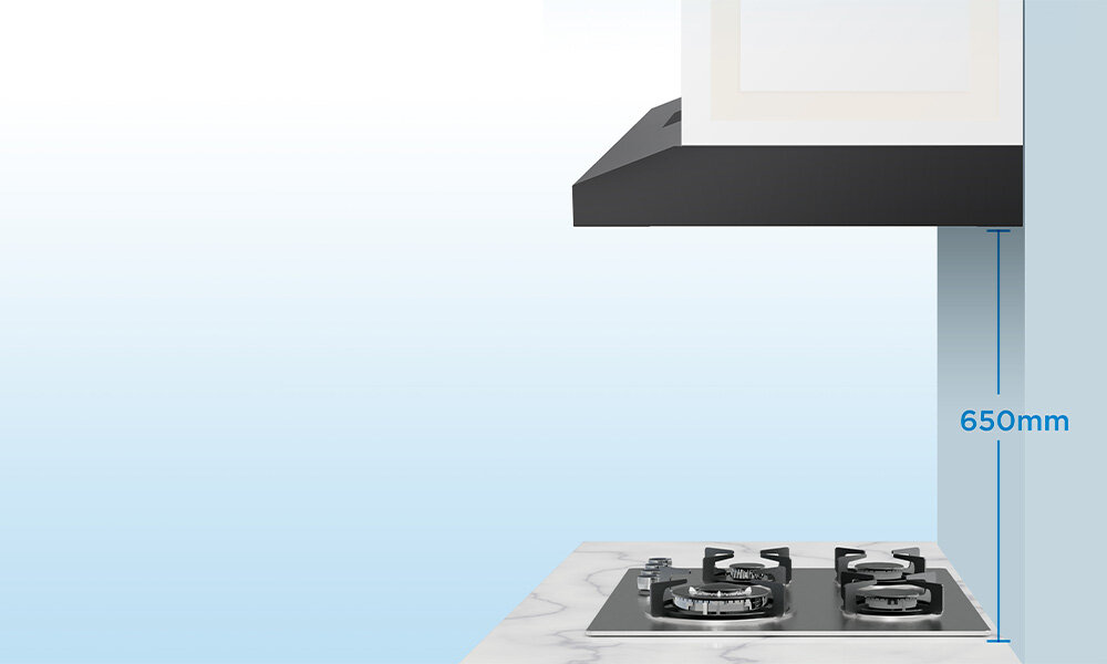 OKAP MIDEA MH60F17EM21BB Zdjęcie przedstawia okap zamontowany nad kuchenką gazową z zaznaczonym pionowym odstępem 650 mm. Obraz pokazuje prawidłową odległość montażową między okapem a płytą kolor czarny wygląd