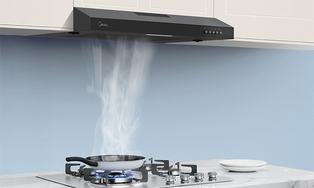 OKAP MIDEA MH60F17EM21BB Ilustracja ukazuje okap pochłaniający parę unoszącą się z patelni podgrzewanej na kuchence gazowej. Widoczny strumień pary podkreśla działanie urządzenia przyciski regulacja skokowa 3 poziomy mocy