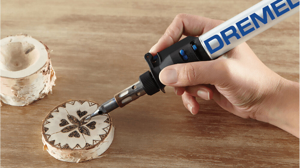 Lutownica DREMEL VersaTip 2000-7 pomieszczenie blat roboczy osoba wypala kształty w drewnianej deseczce zapalnik piezoelektryczny zabezpieczenie chroni przed przypadkowym zapłonem zabezpieczenie chroni przed przypadkowym zapłonem nagrzewanie trwa około 25 sekund oszczędność czasu i płynność pracy
