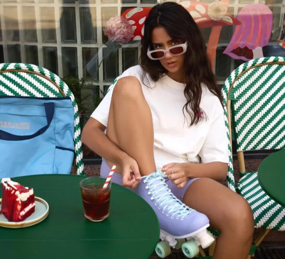 Wrotki SPOKEY Queenie 944634 (rozmiar 30-34) kawiarnia osoba we wrotkach na stopach siedzi przed kawiarnią na krześle stylowa jazda uniwersalność wszechstronna zabawa