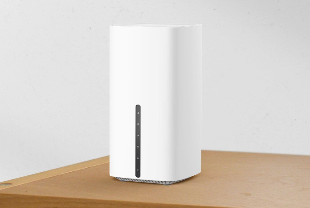 Router TP-LINK Archer NX210 5G Biały router o minimalistycznym wyglądzie stoi na drewnianym blacie, na jasnym tle ściany, modem 5G, przepustowość, łączność LTE