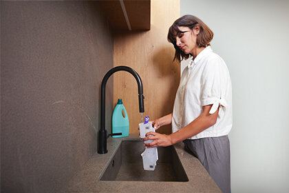 Kobieta uzupełnia zbiornik odkurzacza 10 GF7540 wodą.