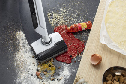 Odkurzacz 10 GF7540 zbierający rozlane sosy, rozsypane przyprawy i jajko w kuchni – Widoczny fragment blatu.