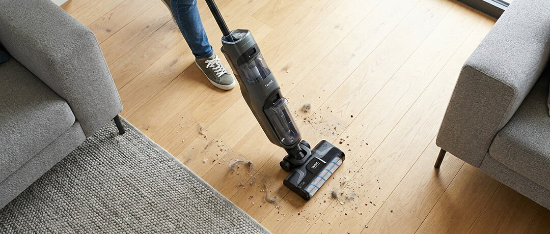 Osoba czyści drewnianą posadzkę z okruszków i sierści odkurzaczem TEFAL X-Clean 4.