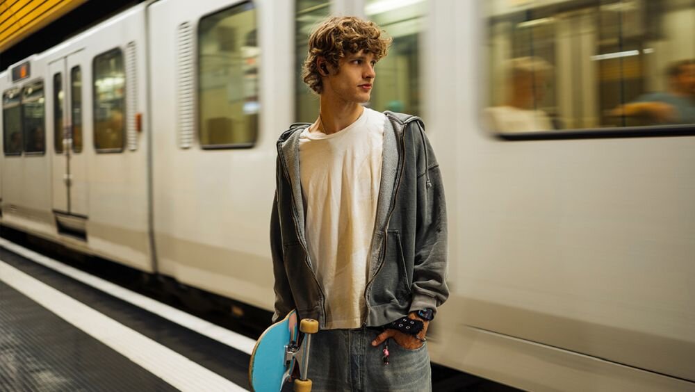 Słuchawki dokanałowe beyerdynamic Amiron 100 ANC Czarny osoba w słuchawkach czekająca na pociąg bluetooth 5.3 le audio automatyczne wstrzymyanie odtwarzanie