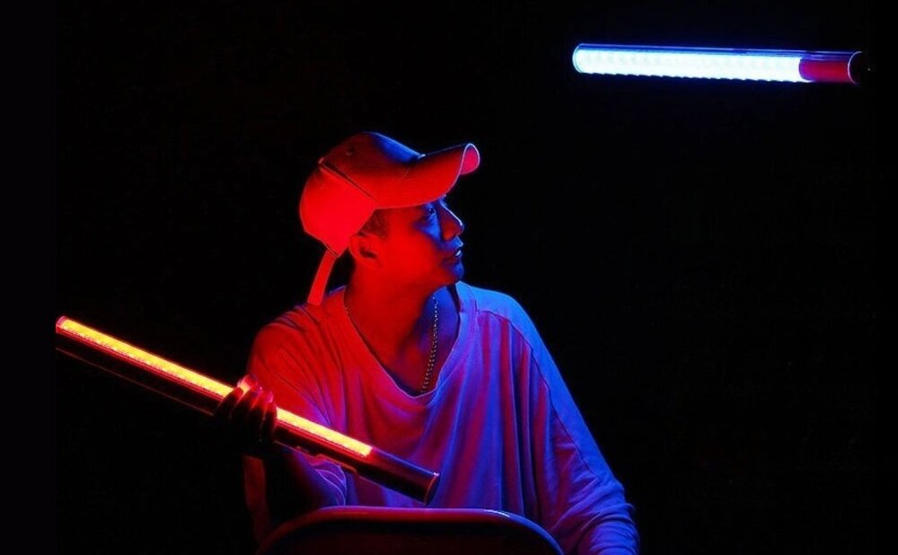 Lampa LED Yongnuo YN360 II - RGB, WB (3200 K - 5600 K) mężczyzna siedzi trzymając lampę YN360II w prawej ręce