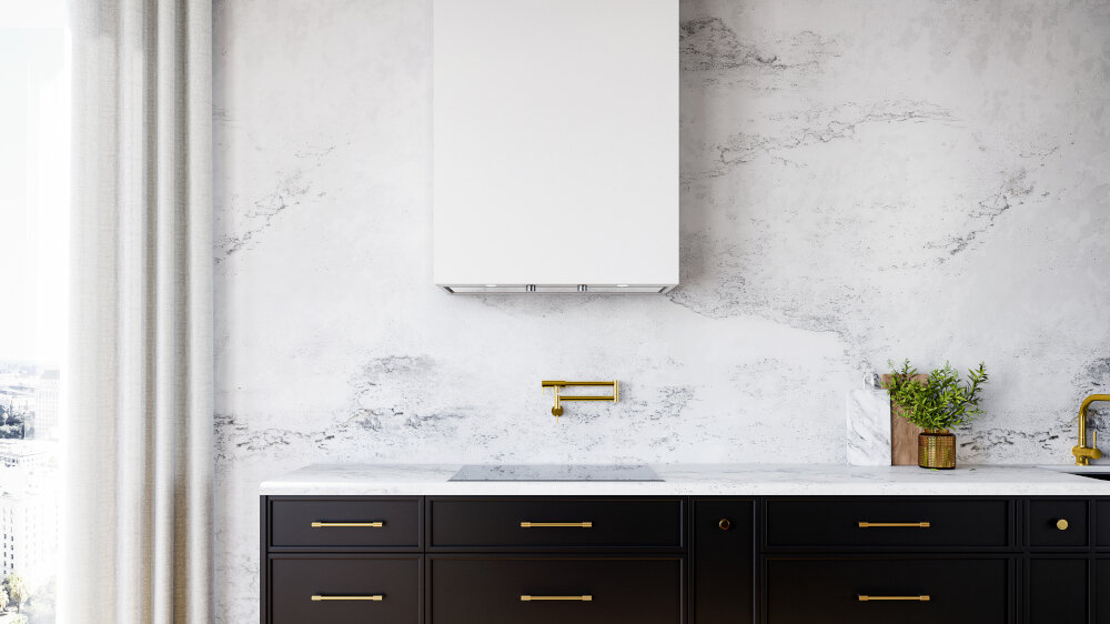 OKAP GLOBALO FLUXIME Obraz ukazuje fragment tej samej kuchni — ścianę roboczą z czarnymi szafkami na dole, marmurowym tłem i białą zabudową wentylacyjną nad płytą. Na blacie stoją dekoracje kuchenne, w tym deska, naczynia oraz zioła w pojemniku. Na środku ściany nad płytą znajduje się złoty, wysuwany kran