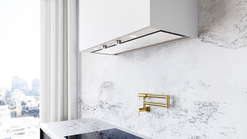 OKAP GLOBALO FLUXIME Zdjęcie stanowi zbliżenie na dolną część białej zabudowy okapu oraz złoty kran nad płytą kuchenną. Widoczne są dwa pokrętła sterujące okapem oraz zewnętrzny widok miasta przez duże okno po lewej stronie, częściowo przysłonięte jasną zasłoną szkło hartowane wyjątkowy design biała stal trwałość elegancka kuchnia