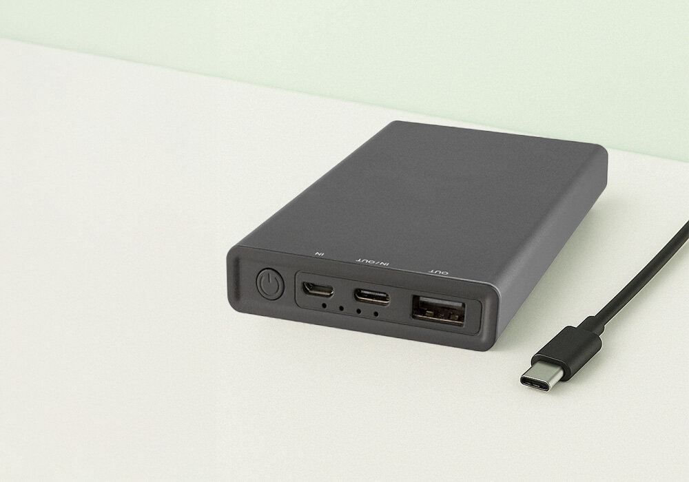 Powerbank QUALO Recycling QRPB5-12-18 5000 mAh Szary, Większy wybór portów, Na zdjęciu powerbank leży na blacie z ekspozycją portów oraz obok leży końcówka kabla USB C