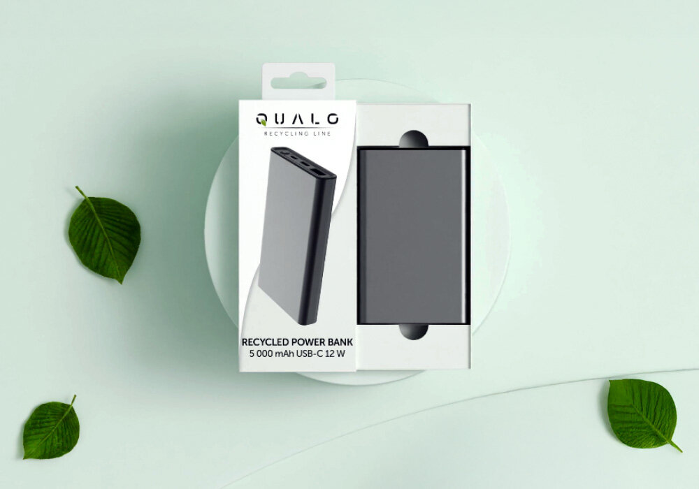 Powerbank QUALO Recycling QRPB5-12-18 5000 mAh Szary, Redukcja plastiku, Na zdjęciu opakowanie powerbanka, do połowy rozpakowane wraz z powerbankiem w środku, obok wizualizacja środowiska, liść