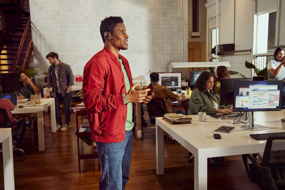 HP Poly Voyager Legend 30 VOY302 mono design świadomość otoczenia, osoba z założoną słuchawką trzymająca smartfon w ręku