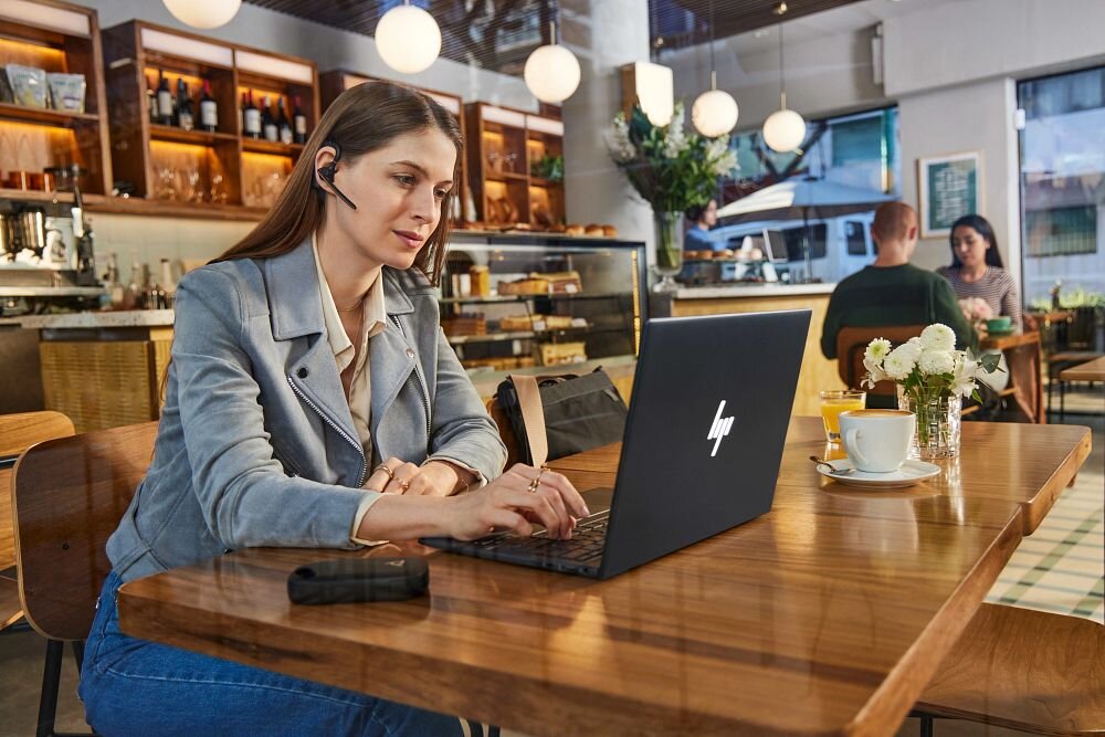 Słuchawka HP Poly Voyager Legend 50 VOY502 mobilność wygoda redukcja hałasu, osoba z założoną słuchawką pracująca na laptopie w pomieszczeniu