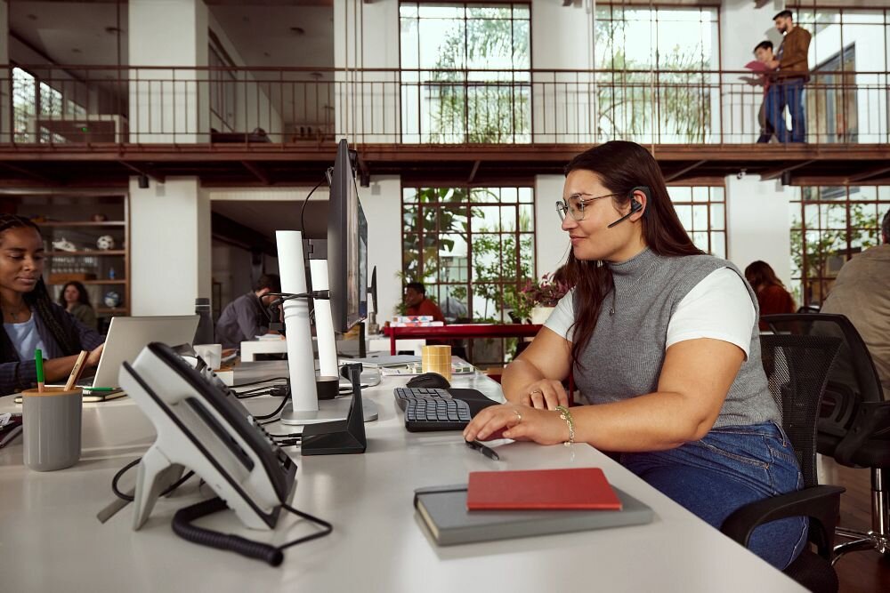 Słuchawka HP Poly Voyager Legend 50 VOY502 ergonomia lekkie wykonanie wkładki douszne, osoba z założoną słuchawką pracująca w biurze