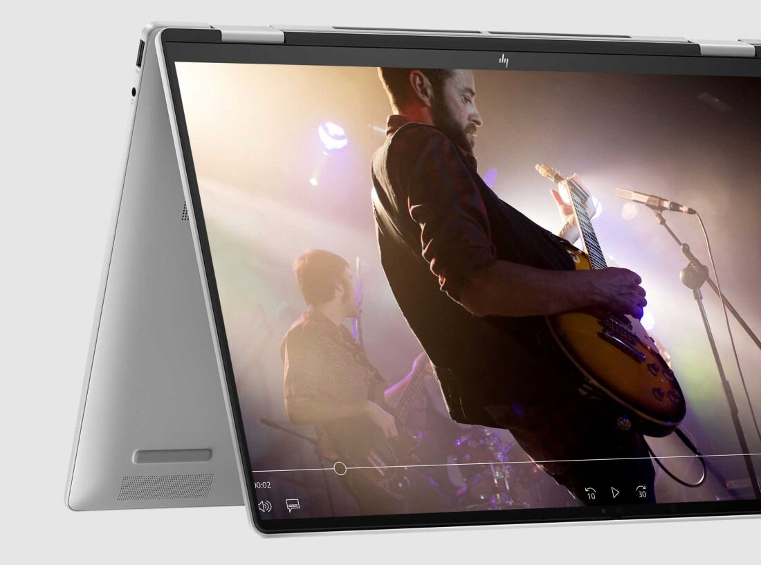 Laptop HP Envy x360 z grafiką przedstawiającą gitarzystę na ekranie. dwa wbudowane głośniki HP Dual Speakers HP Audio Boost
