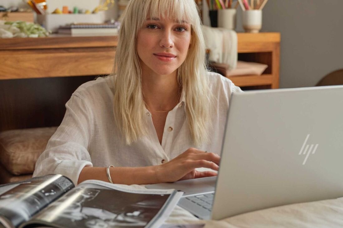 Kobieta siedzi przy biurku z laptopem HP Envy x360, skupiona na pracy. Copilot w systemie Windows 