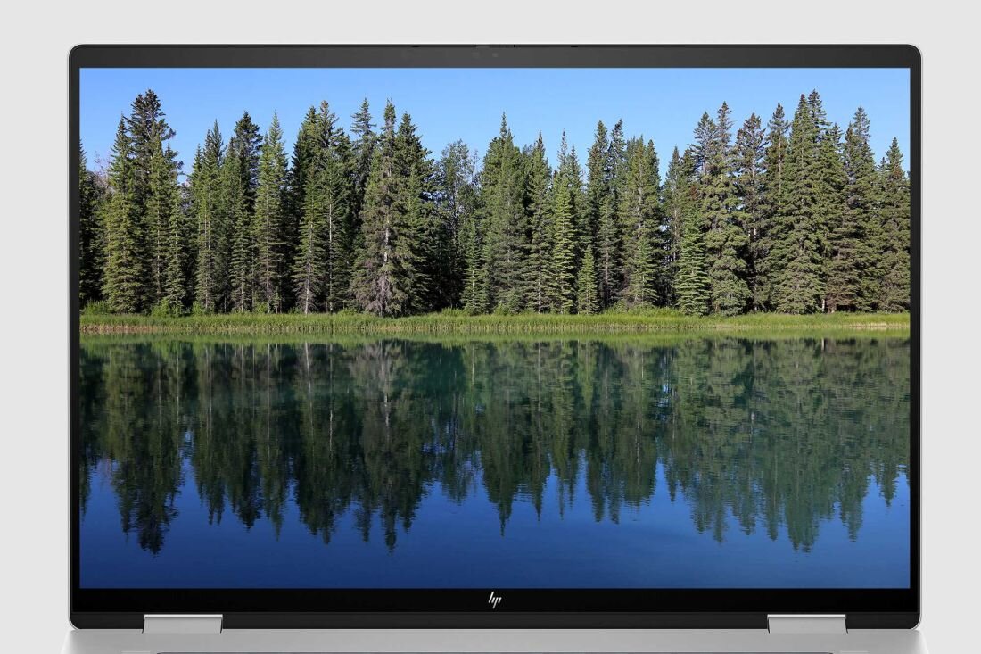 Laptop HP Envy x360 z wyświetlaczem przedstawiającym jezioro otoczone drzewami. Ekran OLED 16 cali rozdzielczość 2880 x 1800 px 