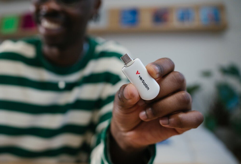 Pendrive VERBATIM Plectra Osoba w pasiaste koszulce trzyma przed sobą czarny pendrive z niebieskim akcentem i widocznym portem USB-C