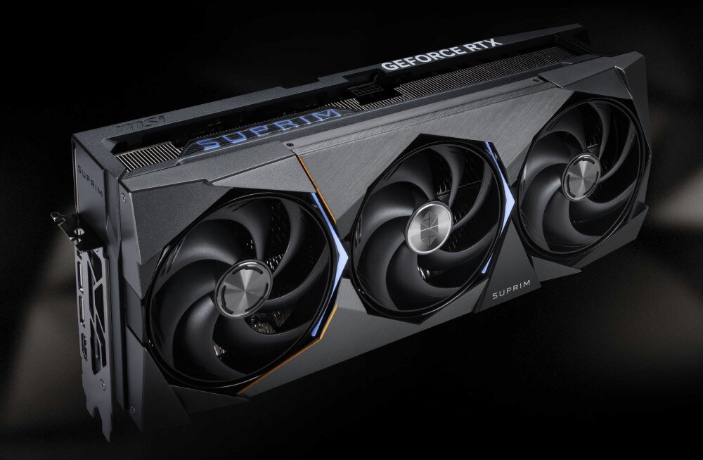 Karta graficzna MSI GeForce RTX 5090 Suprim SOC 32GB Karta graficzna sfotografowana pod kątem, pokazująca trzy wentylatory oraz górną część obudowy z napisami GeForce RTX i Suprim. Obudowa ma wyraziste linie i metaliczne wykończenie, wydajność, rdzenie CUDA, pamięć VRAM, Dual BIOS