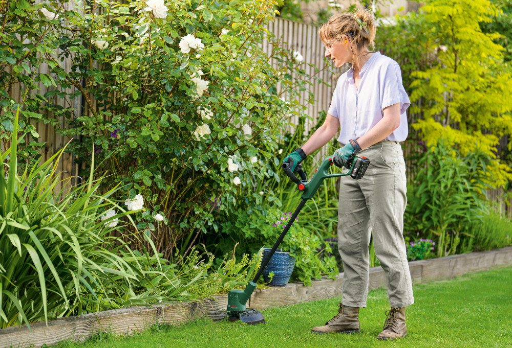 Podkaszarka akumulatorowa BOSCH EasyGrassCut 18V-230 0.600.8C1.A06 ogród rośliny płot osoba podcina trawę wzdłuż ogrodzenia do precyzyjnego przycinania swoboda pracy zadbany ogród
