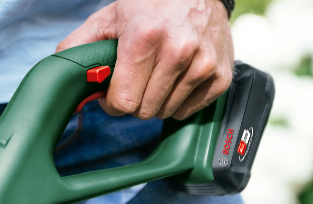 Podkaszarka akumulatorowa BOSCH EasyGrassCut 18V-230 0.600.8C1.A06 zbliżenie na uchwyt główny osoba trzyma podkaszarkę w dłoni waga 2,2 kg dobre wyważenie poziom hałasu 80 dB