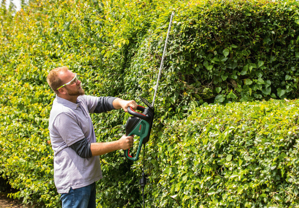 Nożyce do żywopłotu BOSCH AdvancedHedgeCut 70 0.600.8C0.905 ogród osoba przycina żywopłot trzymając nożyce w górze silnik szczotkowy o mocy 500 W wysoka prędkość skokowa do 3.400 min⁻¹ przycinać całe odcinki żywopłotu w krótszym czasie